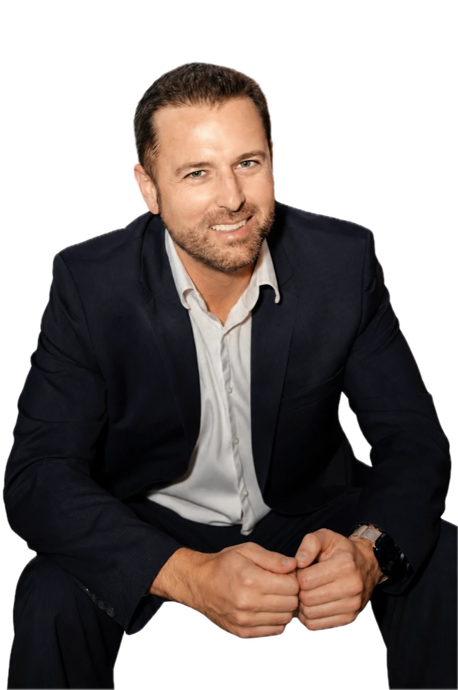 Chris Danton, seated and smiling, dark jacket and open-collar shirt.
